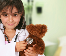 young girl playing doctor with teddy bear